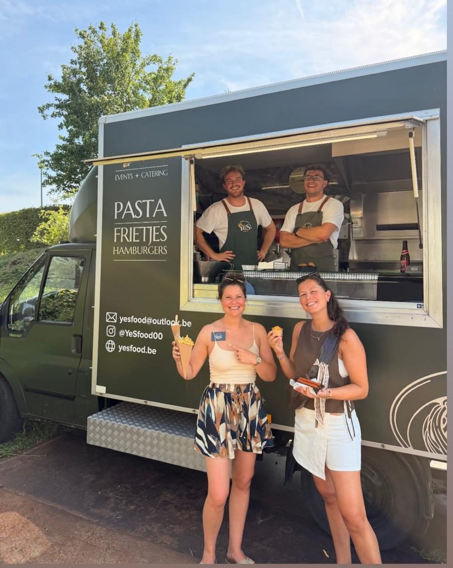 Gasten met frietjes voor de YES Food-foodtruck op een zomers event